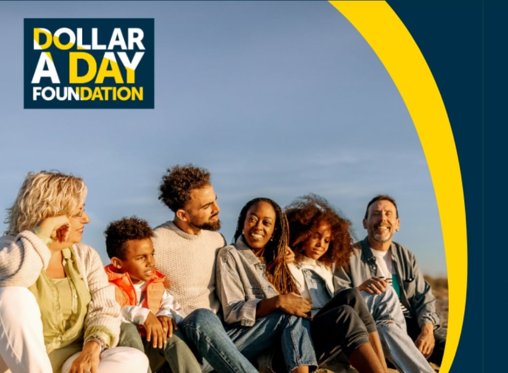 A group of people smiling with the A Dollar A Day Foundation logo.