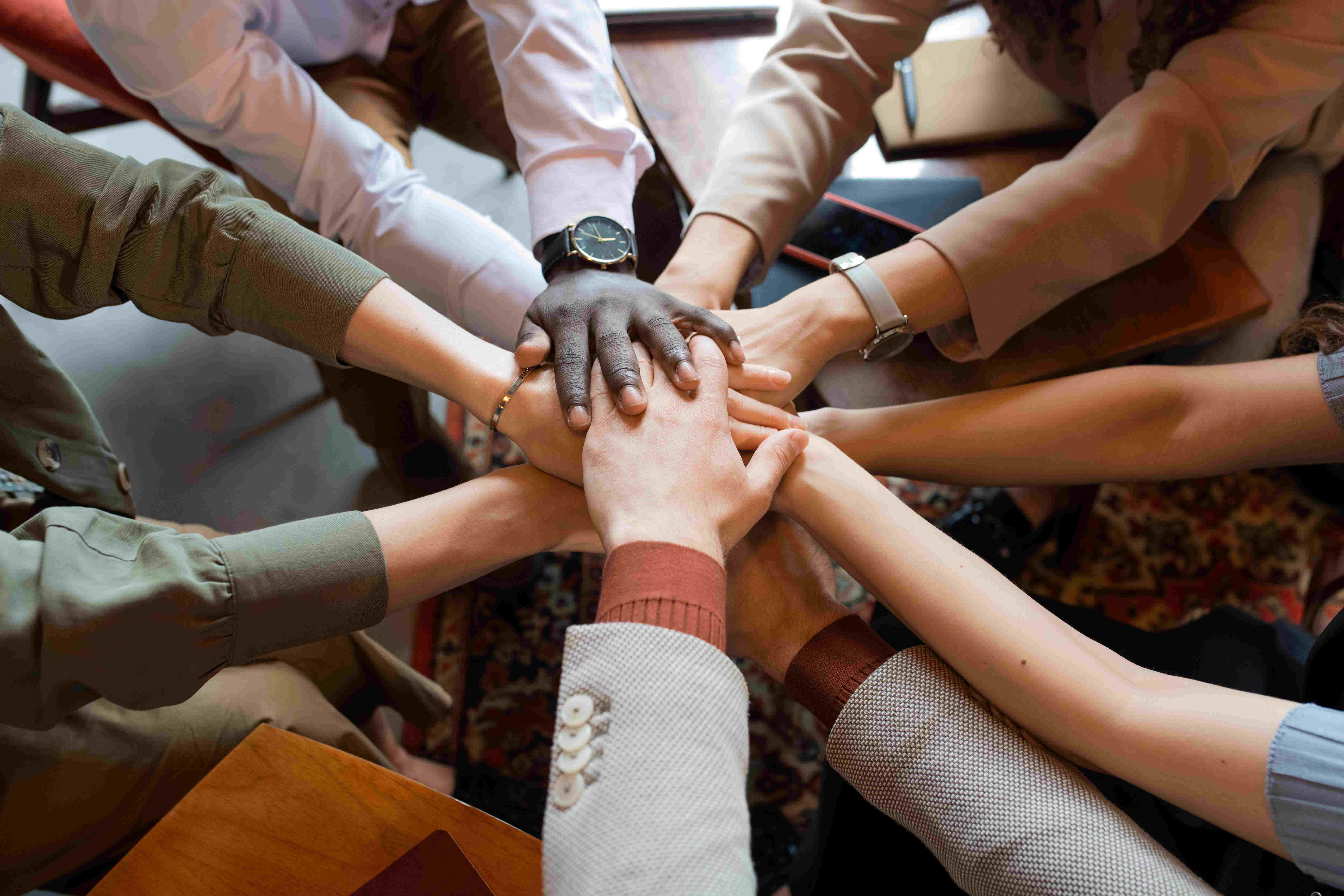 Multiple diverse hands stacked on top of each other to show unity.