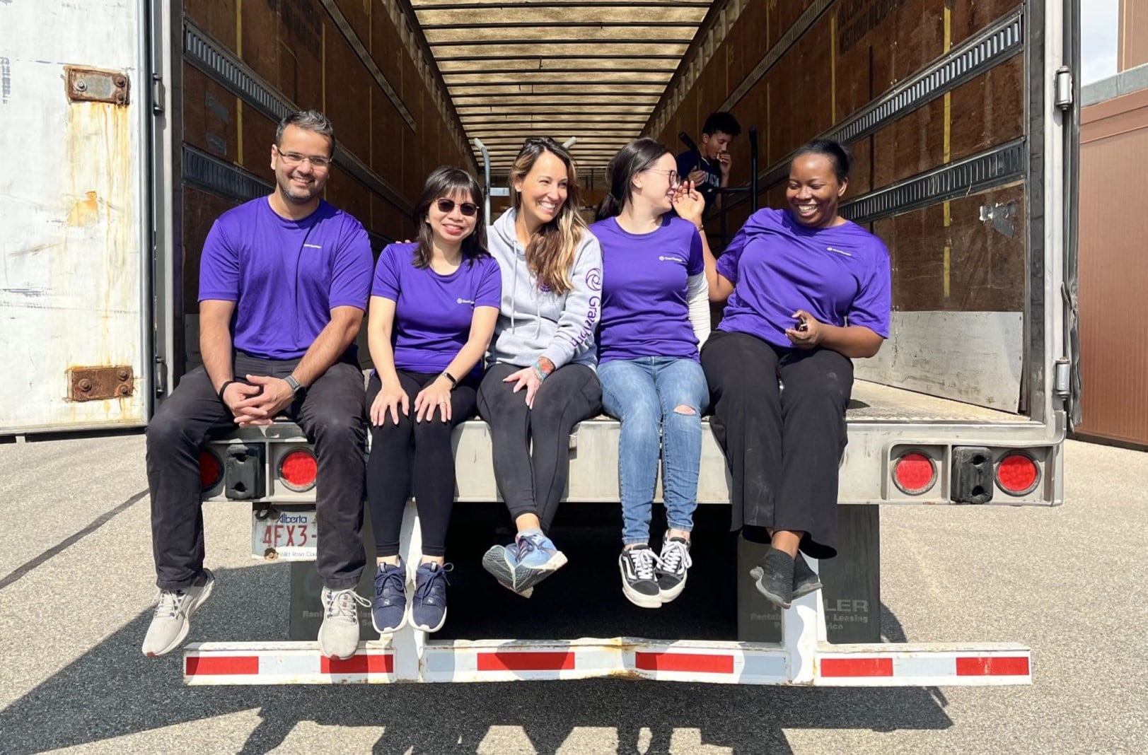 Five Doane Grant Thornton colleagues sit in the back of a delivery truck after volunteering.